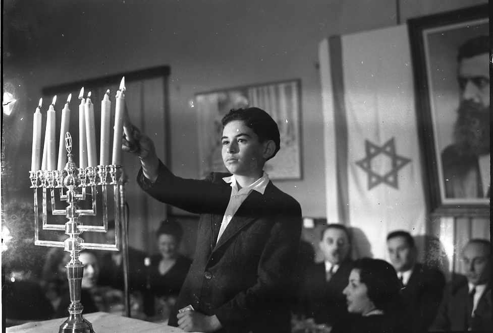 Мальчик поджигает свечи в ханукии во время праздника, организованного МИД Израиля..jpg